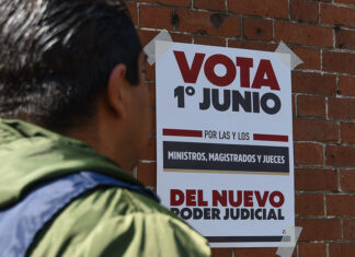 A man looks at a poster reading "Vote June 1 for the new judicial power" in Spanish