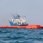 Pemex boats tow floating booms to clean up an oil spill