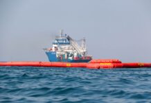 Pemex boats tow floating booms to clean up an oil spill