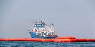 Pemex boats tow floating booms to clean up an oil spill