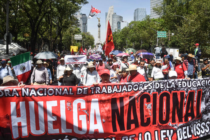 Teachers march down Reforma Avenue in Mexico City with a banner reading 