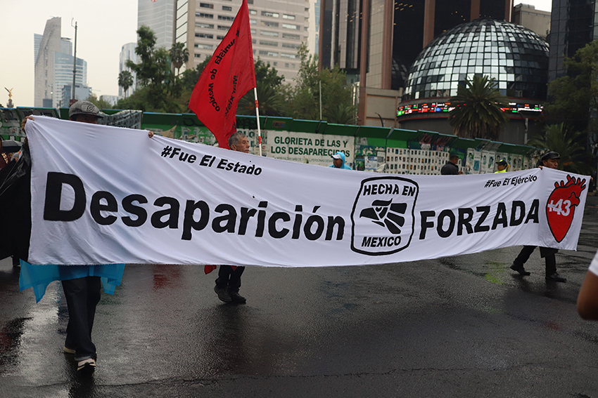 Ayotzinapa protesters carry a banner reading "Desaparicion forzada"