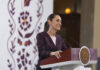 Sheinbaum smiles from behind a podium during her morning press conference