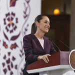 Sheinbaum smiles from behind a podium during her morning press conference