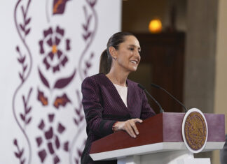Sheinbaum smiles from behind a podium during her morning press conference