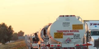 Oil tankers drive down a highway at sunset