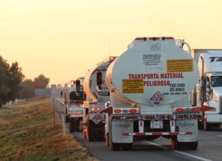 Oil tankers drive down a highway at sunset
