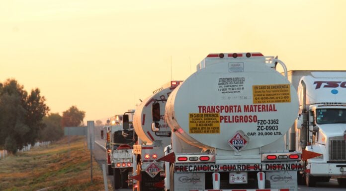 Oil tankers drive down a highway at sunset
