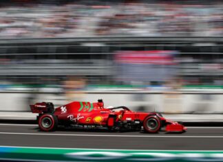A Formula 1 race car speeds through an out-of-focus stadium in Mexico City