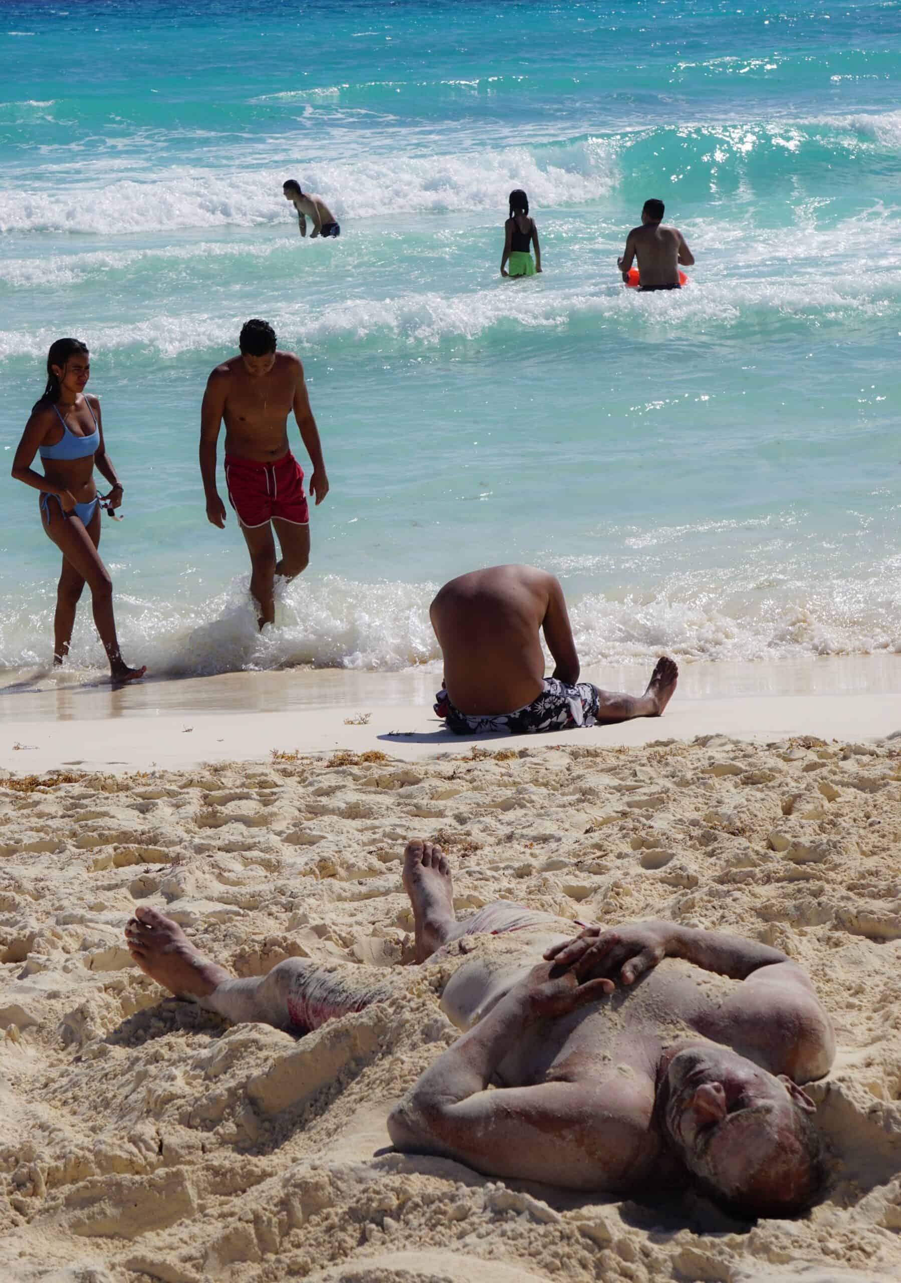 A man rests in the sand on a Cancún beach