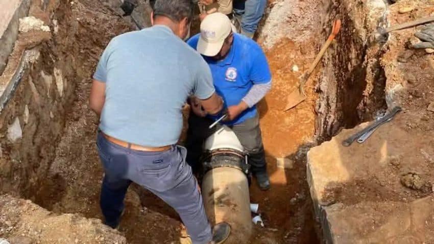 Workmen in a deep trench standing on and next to water infrastructure pipes in San Cristobal de las Casas, Chiapas, in Mexico