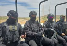 Agents in black helmets and bulletproof vests ride through the Sinaloa countryside on a military-type transport