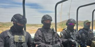 Agents in black helmets and bulletproof vests ride through the Sinaloa countryside on a military-type transport