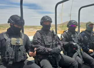 Agents in black helmets and bulletproof vests ride through the Sinaloa countryside on a military-type transport