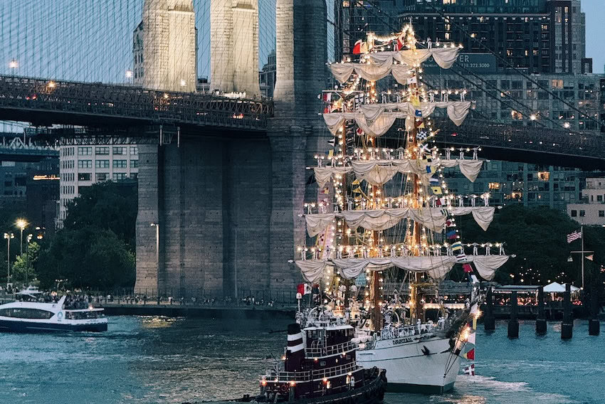 ship with sails by bridge