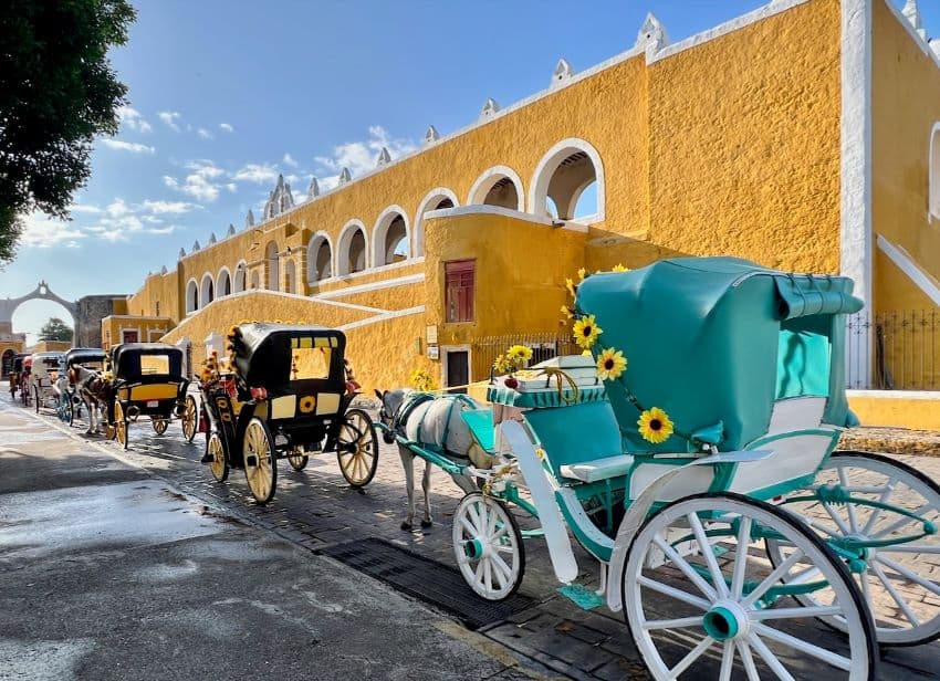 Line of horse-drawn carriages in front of a building in Izamal