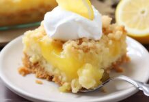 A slice of lemon cake with whipped cream and a fork