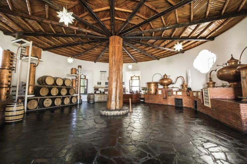 A comprehensive round wine -making room with wine barrels on shelves and various antique copper and brass wine.
