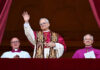 Pope Leo XIV in full regalia waves from a balcony
