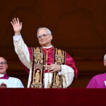 Pope Leo XIV in full regalia waves from a balcony