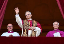 Pope Leo XIV in full regalia waves from a balcony