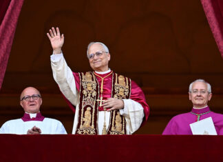 Pope Leo XIV in full regalia waves from a balcony