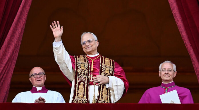 Pope Leo XIV in full regalia waves from a balcony