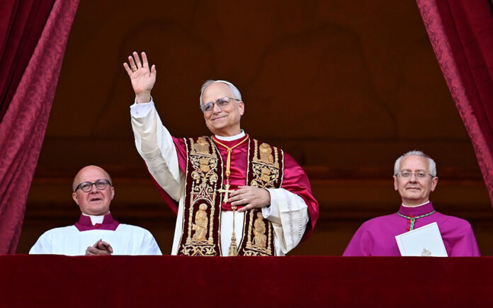 Pope Leo XIV in full regalia waves from a balcony