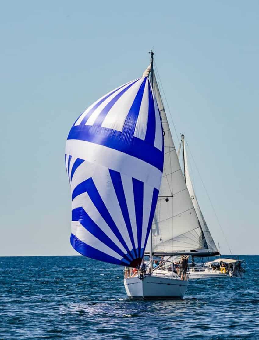 A sailboat with blue and white striped sails in the ocean