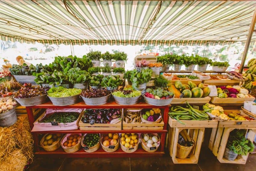 A farmer's market store at Flora Farms near San Jose del Cabo, Baja California Sur in Mexico. In a canopied outdoor one-room structure, shelves of wooden crates display an overflowing amount of varied fresh, healthy produce.