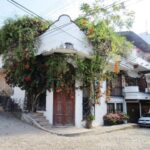 An adobe home with colonial-style carved wooden double doors ists on a street corner in downtown Puerto Vallarta