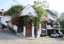 An adobe home with colonial-style carved wooden double doors ists on a street corner in downtown Puerto Vallarta