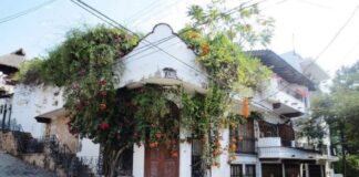 An adobe home with colonial-style carved wooden double doors ists on a street corner in downtown Puerto Vallarta