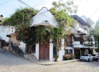 An adobe home with colonial-style carved wooden double doors ists on a street corner in downtown Puerto Vallarta