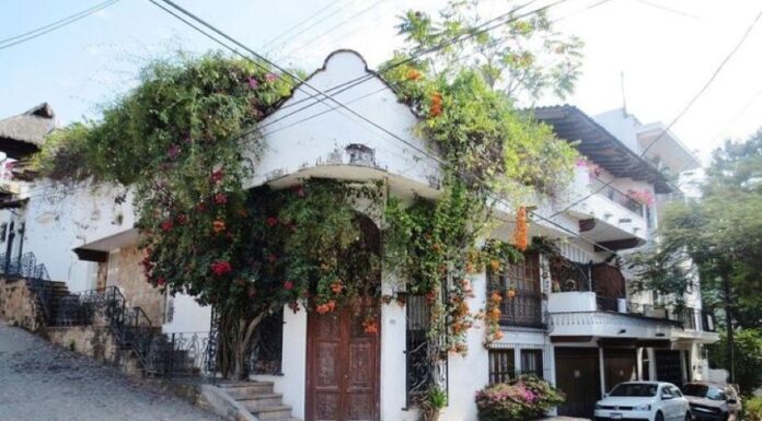 An adobe home with colonial-style carved wooden double doors ists on a street corner in downtown Puerto Vallarta