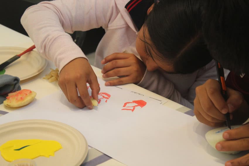 A Mexican baby creates volume printed designs on white paper.
