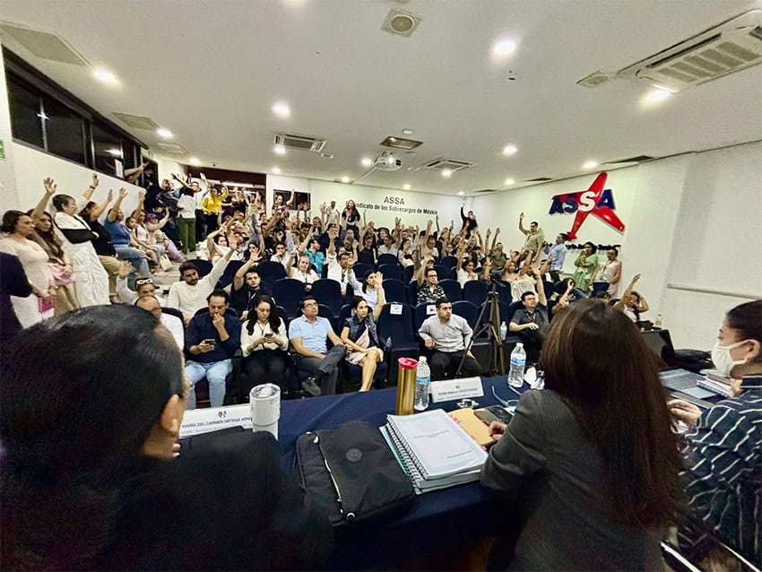 A room full of people raises their hands at a meeting
