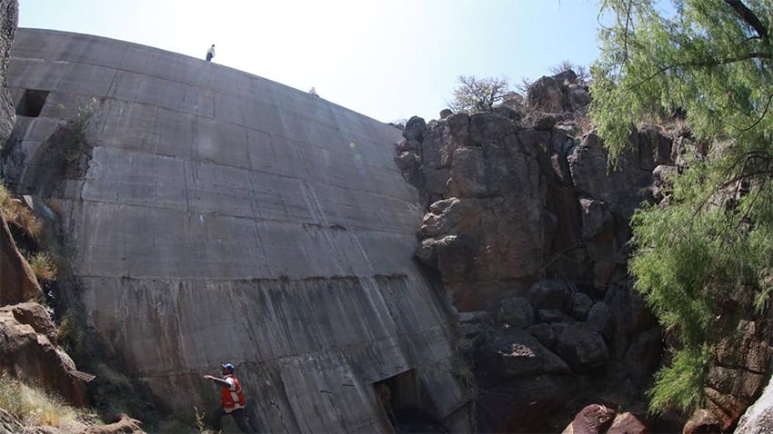 A government worker stands at the bottom of a roughly 10-meter dam
