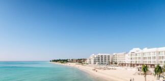 A white sand beach with turquoise water and condo towers in the Riviera Maya