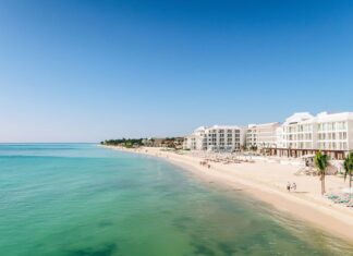A white sand beach with turquoise water and condo towers in the Riviera Maya