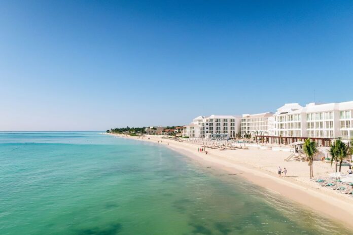 A white sand beach with turquoise water and condo towers in the Riviera Maya