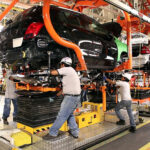 Factory workers assemble a car