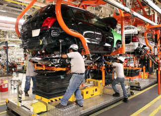 Factory workers assemble a car