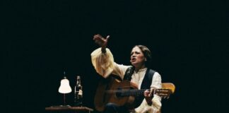 Natalia Lafourcade seated onstage with guitar during Cancionera tour