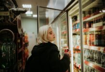 Woman opens a fridge in a convenience store
