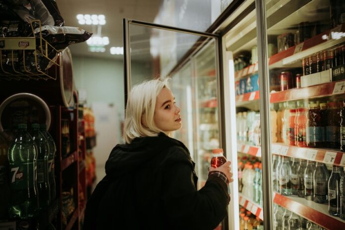 Woman opens a fridge in a convenience store