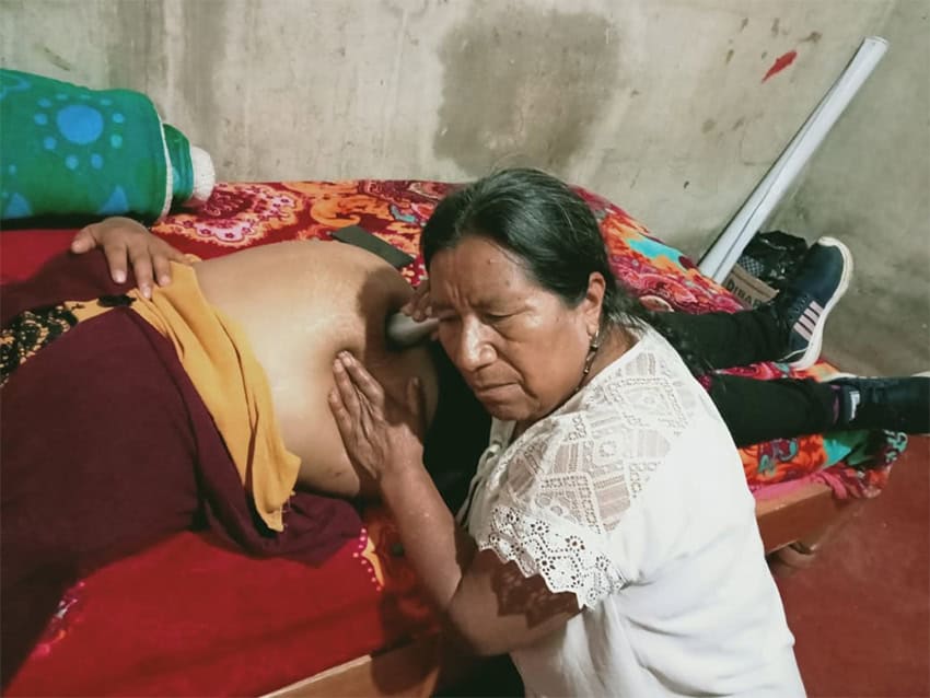 A Chiapas midwife listens for the heartbeat of a baby near its due date.