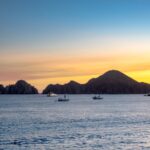 Sunset over the ocean in Cabo San Lucas with sailboats in the water