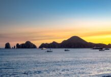 Sunset over the ocean in Cabo San Lucas with sailboats in the water