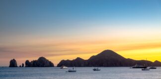 Sunset over the ocean in Cabo San Lucas with sailboats in the water